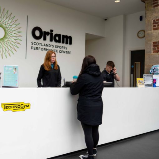 Receptionist talking to member at Oriam reception desk.