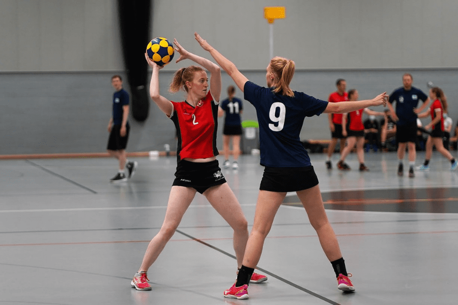 Image Credit Scotland Korfball. Two female players from opposing teams on court with Korfball. 
