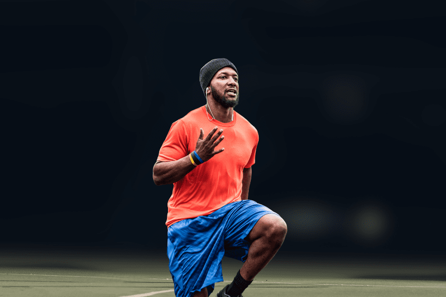 Tennis Warmup Close-up of man doing high knees exercise. soft blurred tennis court in background.
